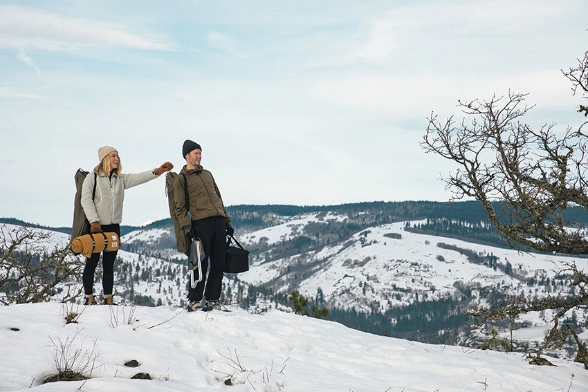 a couple on a snowy hill with snow peak x rumpl nanoloft takibi blanket